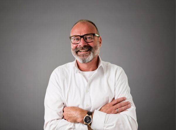 Mitarbeiterportrait von Volker Klosowski vor grauem Hintergrund.