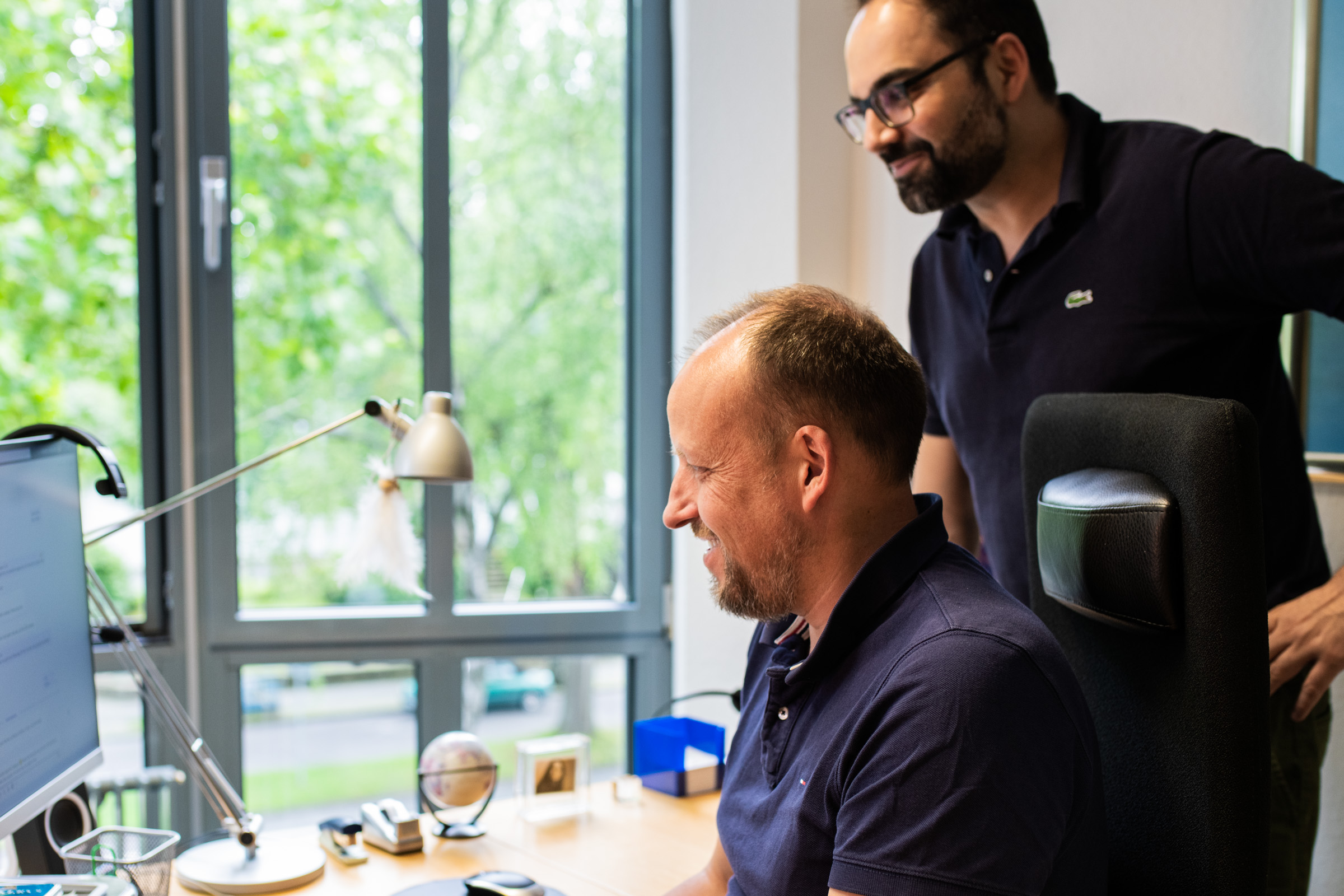 Dr. Johannes Wamser und Mike D. Batra schauen gemeinsam auf einen Monitor im Wamser + Batra HQ Bochum.