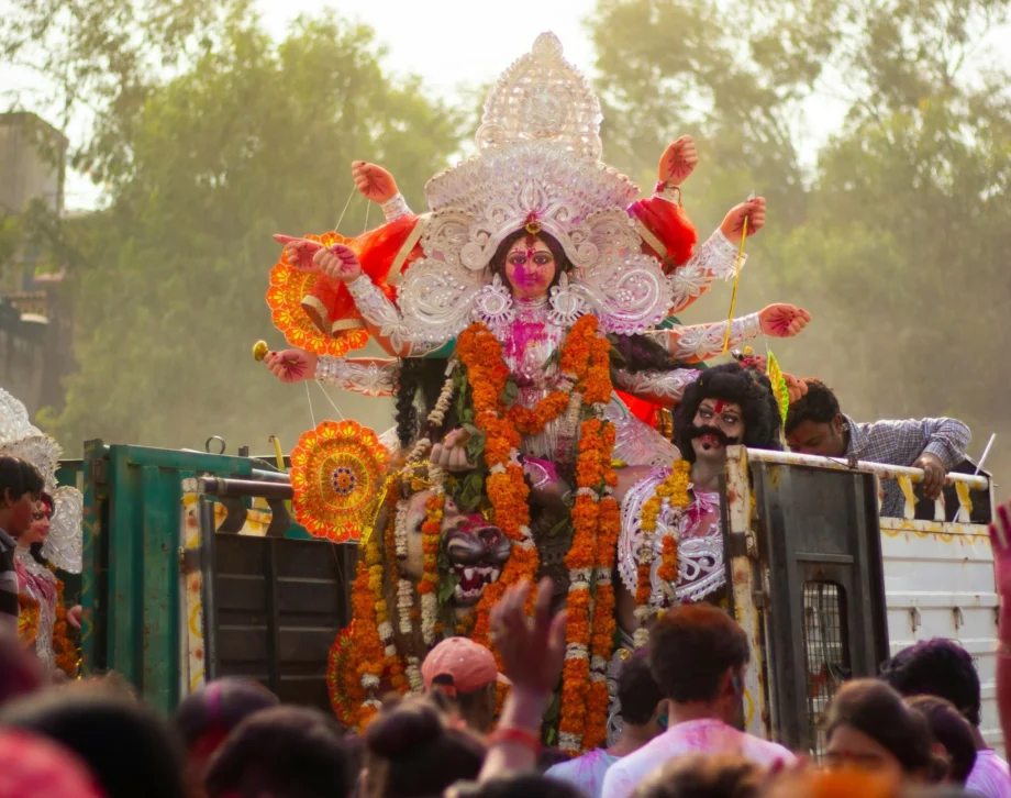 Hinduistisches Straßenfest. Prachtvoll geschmückte Statue der Göttin Lakshmi auf einem Lkw, Ansammlung von Menschen davor.
