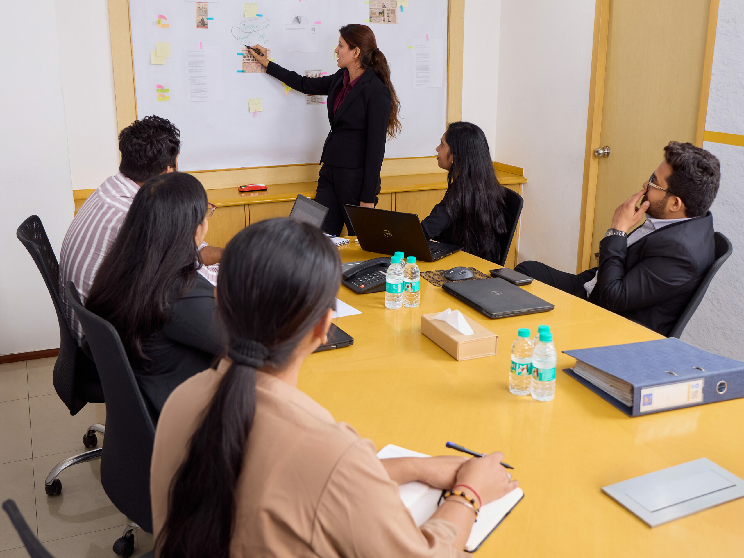 Eine Mitarbeiterin erläutert ihren Kolleginnen und Kollegen eine Strategie am Flipchart im Konferenzraum des Wamser + Batra HQ Delhi.
