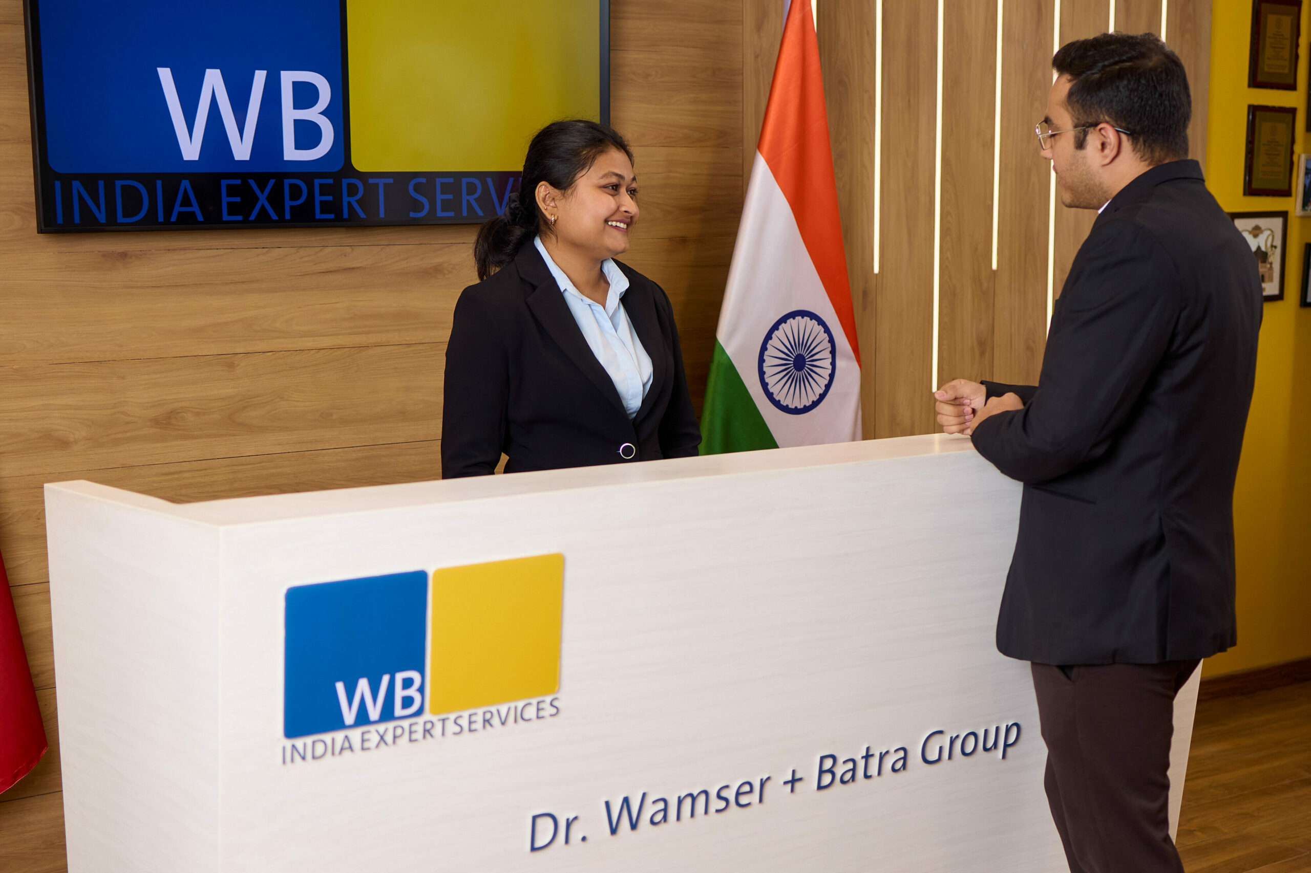 Ein Kunde wird von einer Mitarbeiterin im Empfangsbereich des Wamser + Batra HQ Delhi begrüßt.